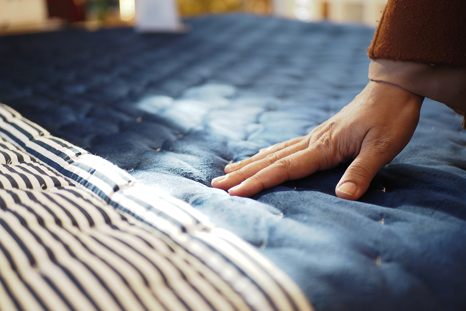 Hand resting on a quilted mattress